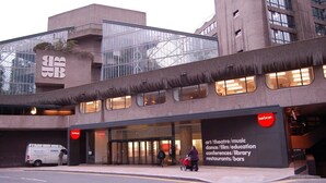 Un bâtiment moderne doté d’une grande entrée en verre et d’une enseigne indiquant qu’il abrite un bar, un restaurant et, éventuellement, une bibliothèque.
