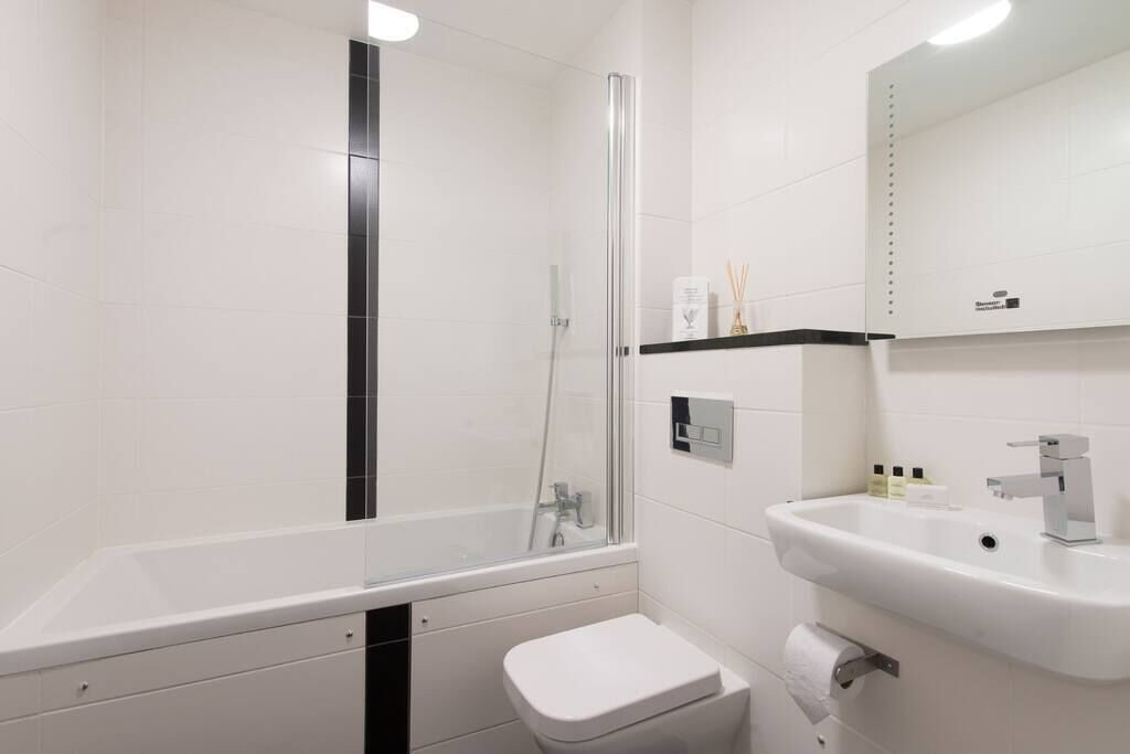 A modern bathroom with a glass-enclosed shower, a white sink, and a toilet.