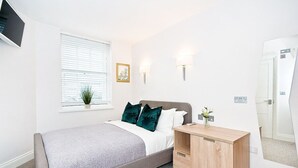 Een slaapkamer met een bed, nachtkastje en een klein kastje.