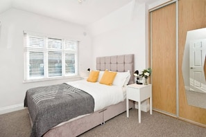 Relax in a serene bedroom with a neatly made bed, bedside table, and a stylish wardrobe.
