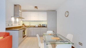 Een compacte keuken met een centraal eiland, witte kasten en een moderne kookplaat.