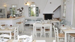 A spacious dining area with white furniture, a fireplace, and a view of the outdoors. - An apartment that sleeps 4 guests  in 1 bedroom (Paros)