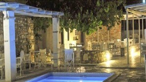A pool area with stone walls and outdoor seating. - An apartment that sleeps 4 guests  in 1 bedroom (Paros)