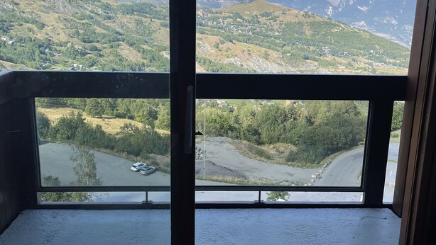 Een kamer met een groot raam met uitzicht op een bergachtig landschap.
