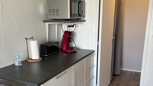 Een kleine keuken met een magnetron, broodrooster en koffiezetapparaat op het aanrecht.