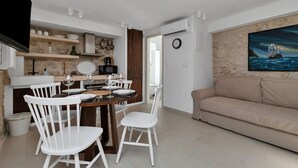 Una cocina moderna con armarios blancos, una mesa de comedor con sillas blancas y un sofá beige.