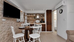 Una cocina moderna con comedor, sillas blancas, televisor de pantalla plana y puerta de madera que da a otra habitación.