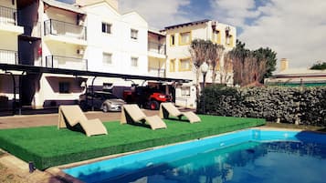 Una piscina al aire libre de temporada, sillones reclinables de piscina