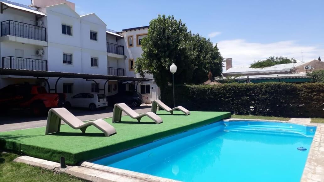 Una piscina con sillones de descanso y un área de césped.