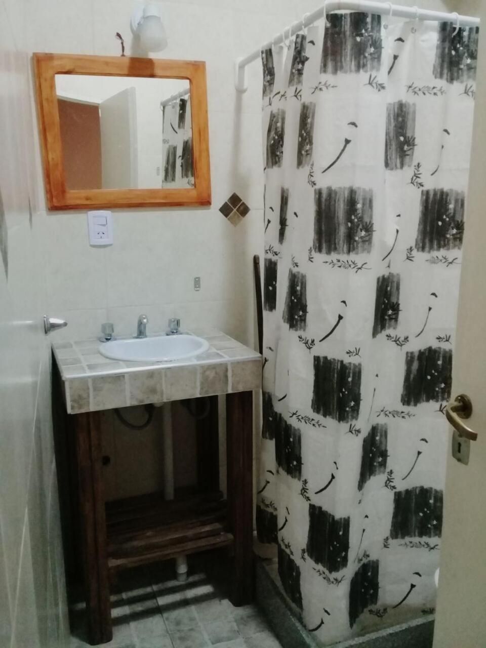 Un baño con lavamanos, espejo y cortina de ducha.