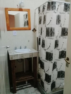 Un baño con lavamanos, espejo y cortina de ducha.