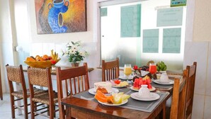 A breakfast table set with plates of fruit, a cake, and a glass of orange juice. - Rede Andrade Porto Center Hotel (Porto Seguro)