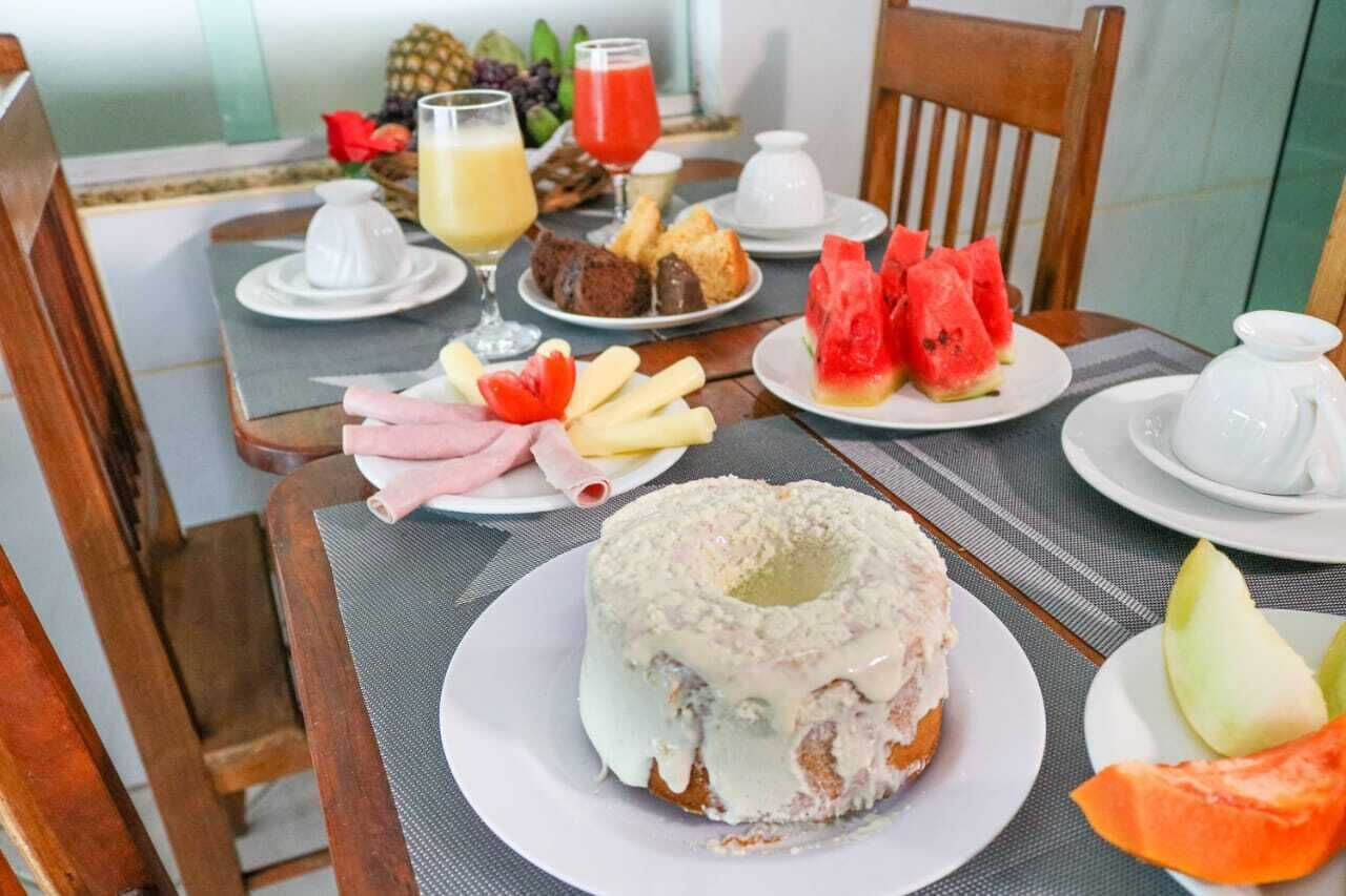 A breakfast table with plates of food, including a cake, fruit, and beverages.
