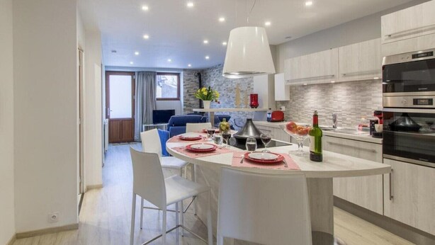 A modern kitchen with a central island, white cabinetry, and built-in appliances.