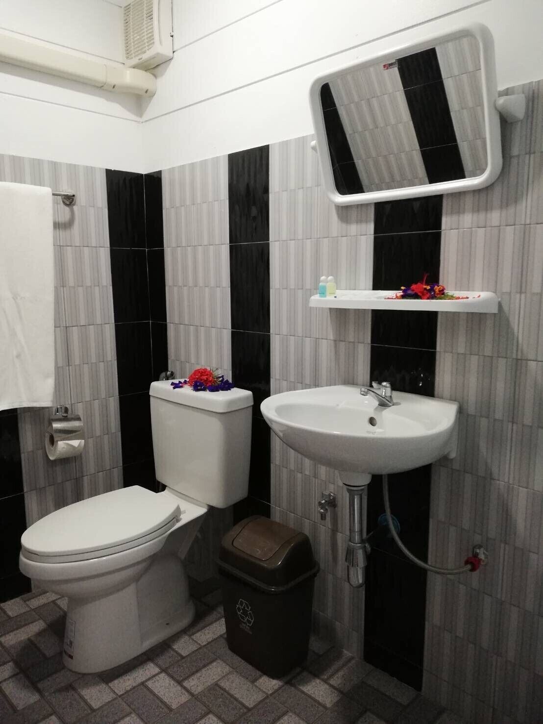 A bathroom with a toilet, sink, and trash bin.
