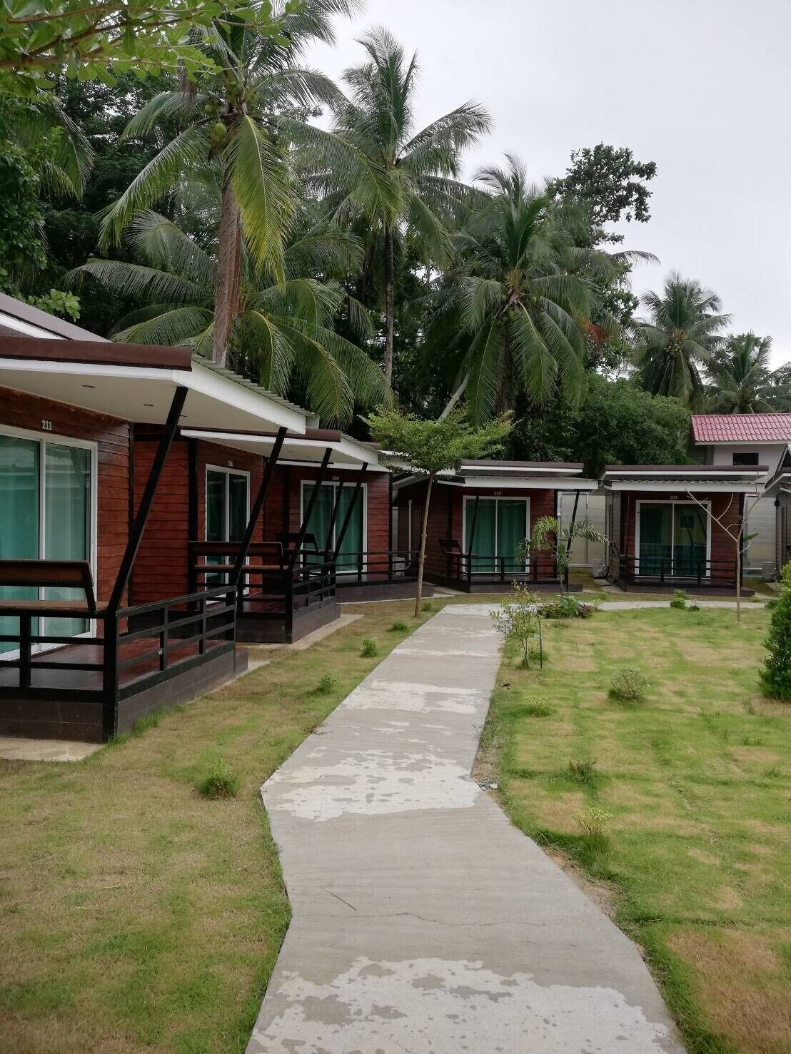 A row of bungalow-style accommodations with a concrete pathway leading to the entrance.