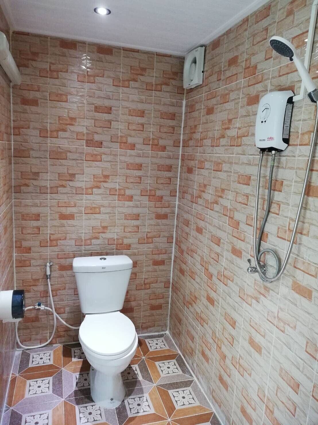 A small bathroom with a toilet, a shower, and a wall-mounted water heater.