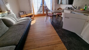 Una sala de estar acogedora con un sofá, una mesa de comedor con sillas y una zona de cocina con microondas.