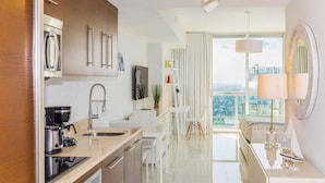 A modern kitchen with a built-in oven, coffee maker, and a large window offering a city view.