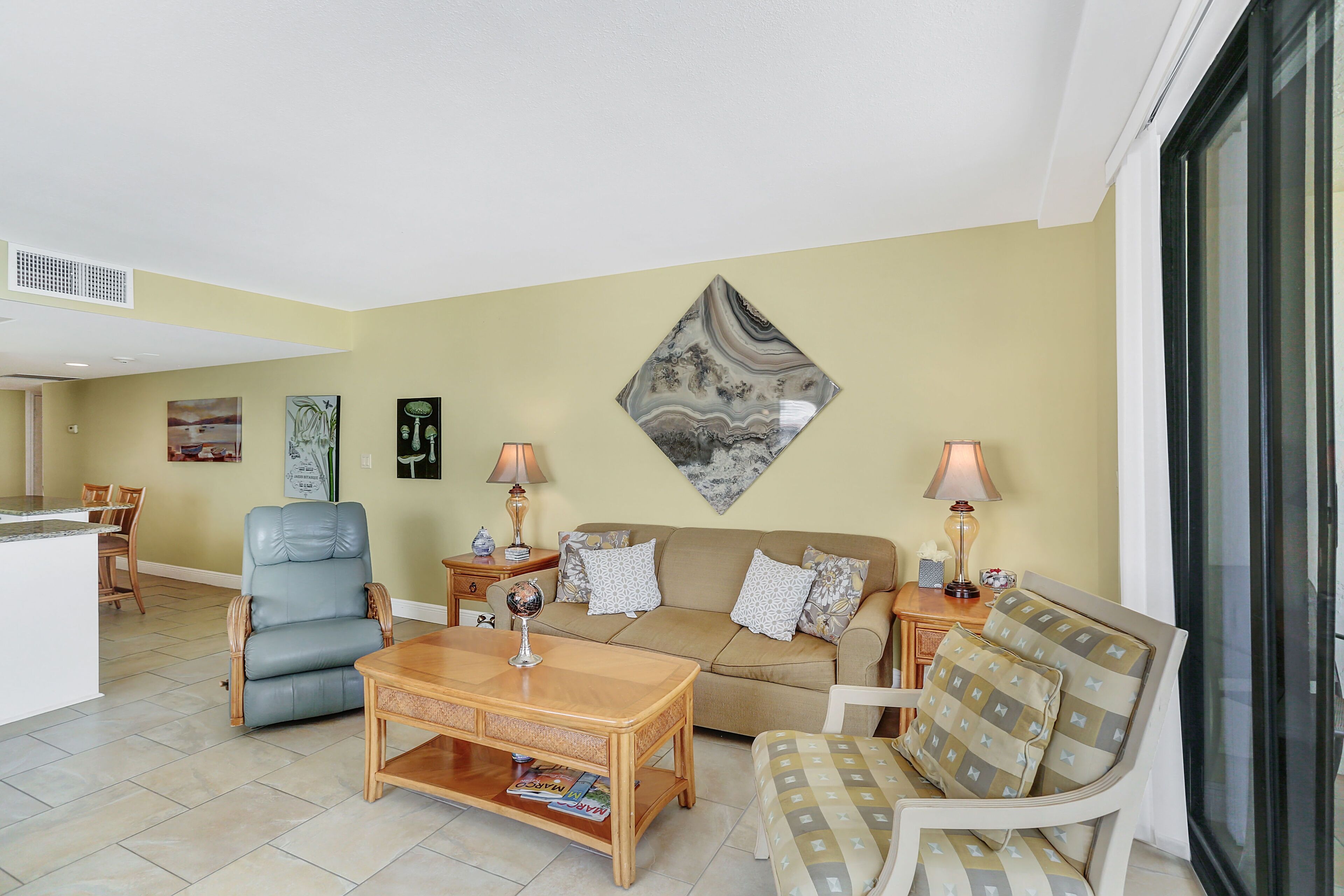 A living room with a sofa, armchairs, a coffee table, and a dining area with chairs.