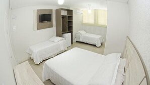 A compact hotel room with a large bed, a smaller bed, a desk, and a wardrobe. - Hotel Natal (Penha)
