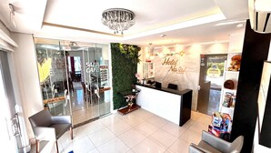 A hotel reception area with a modern design, including a reception desk, seating area, and a decorative wall. - Hotel Natal (Penha)