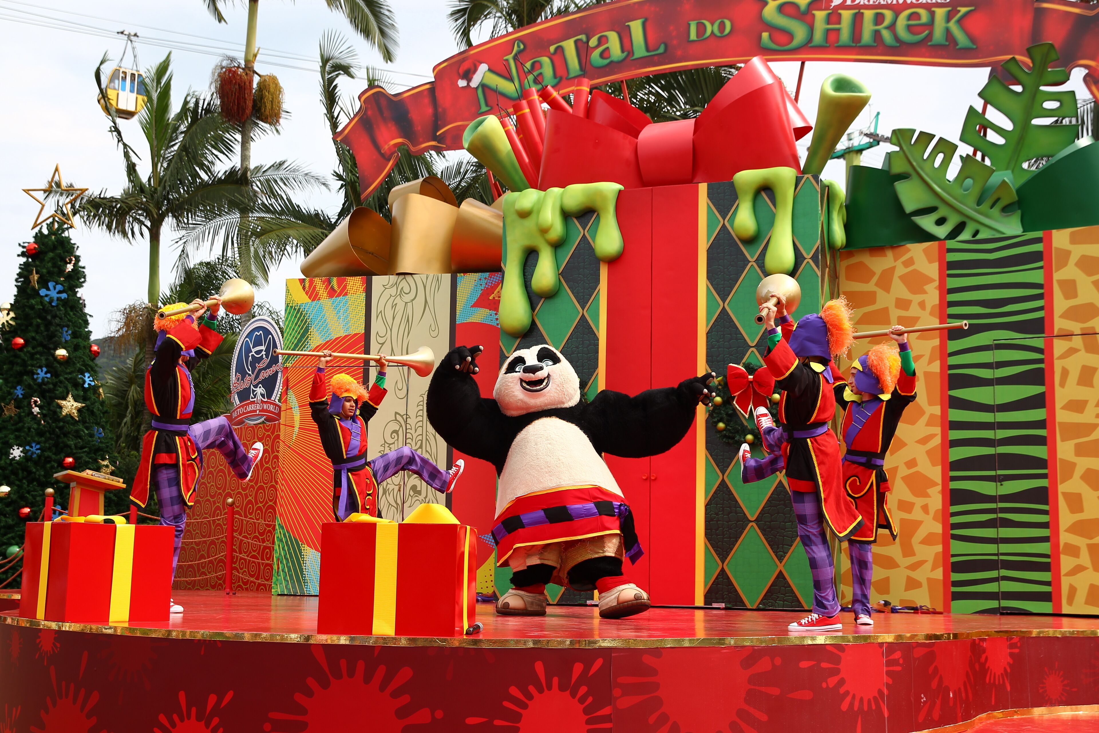 A stage with a large panda character, gift boxes, and performers in colorful costumes.