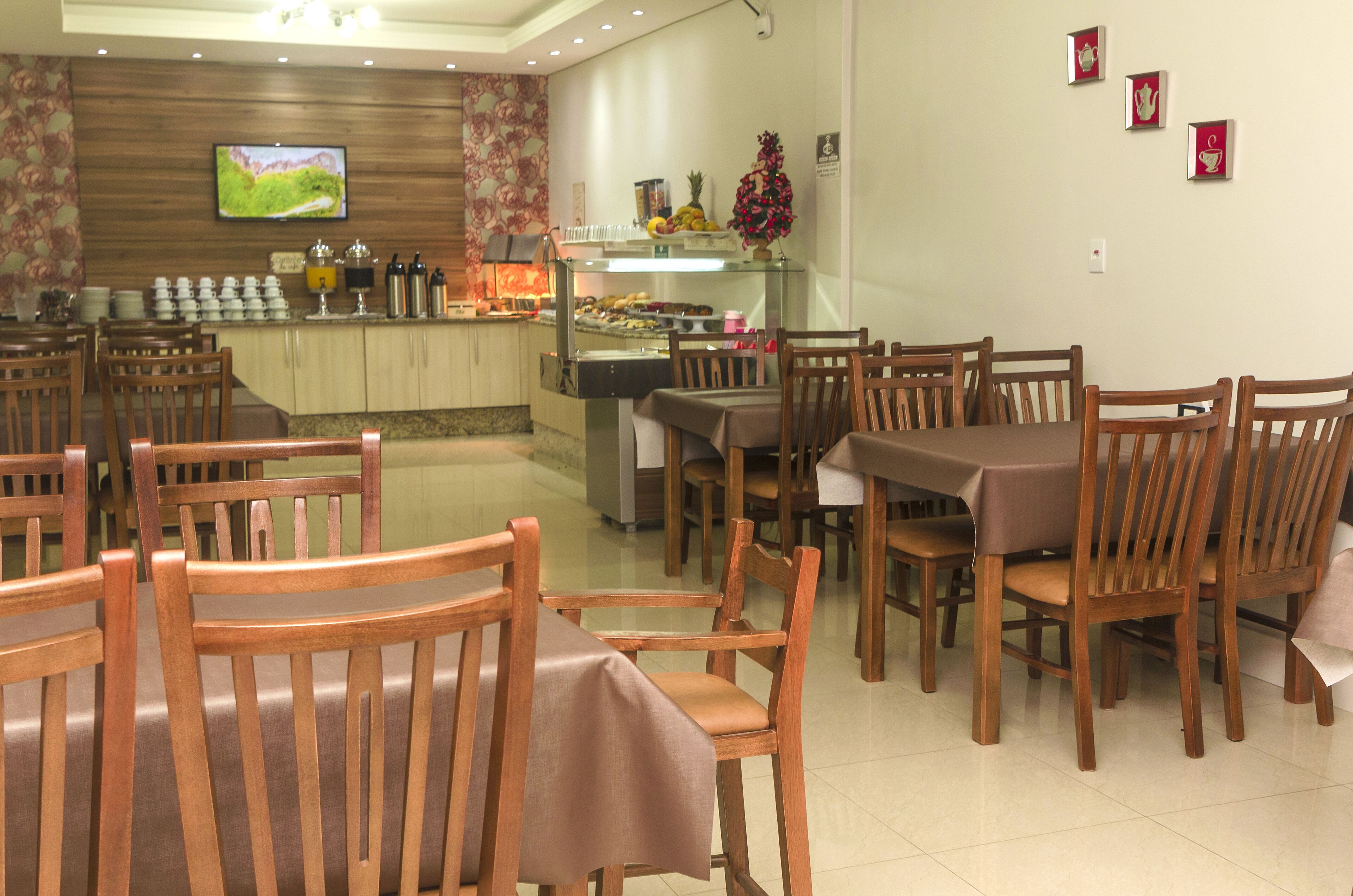 A restaurant with wooden chairs and tables, a buffet counter, and a television on the wall.