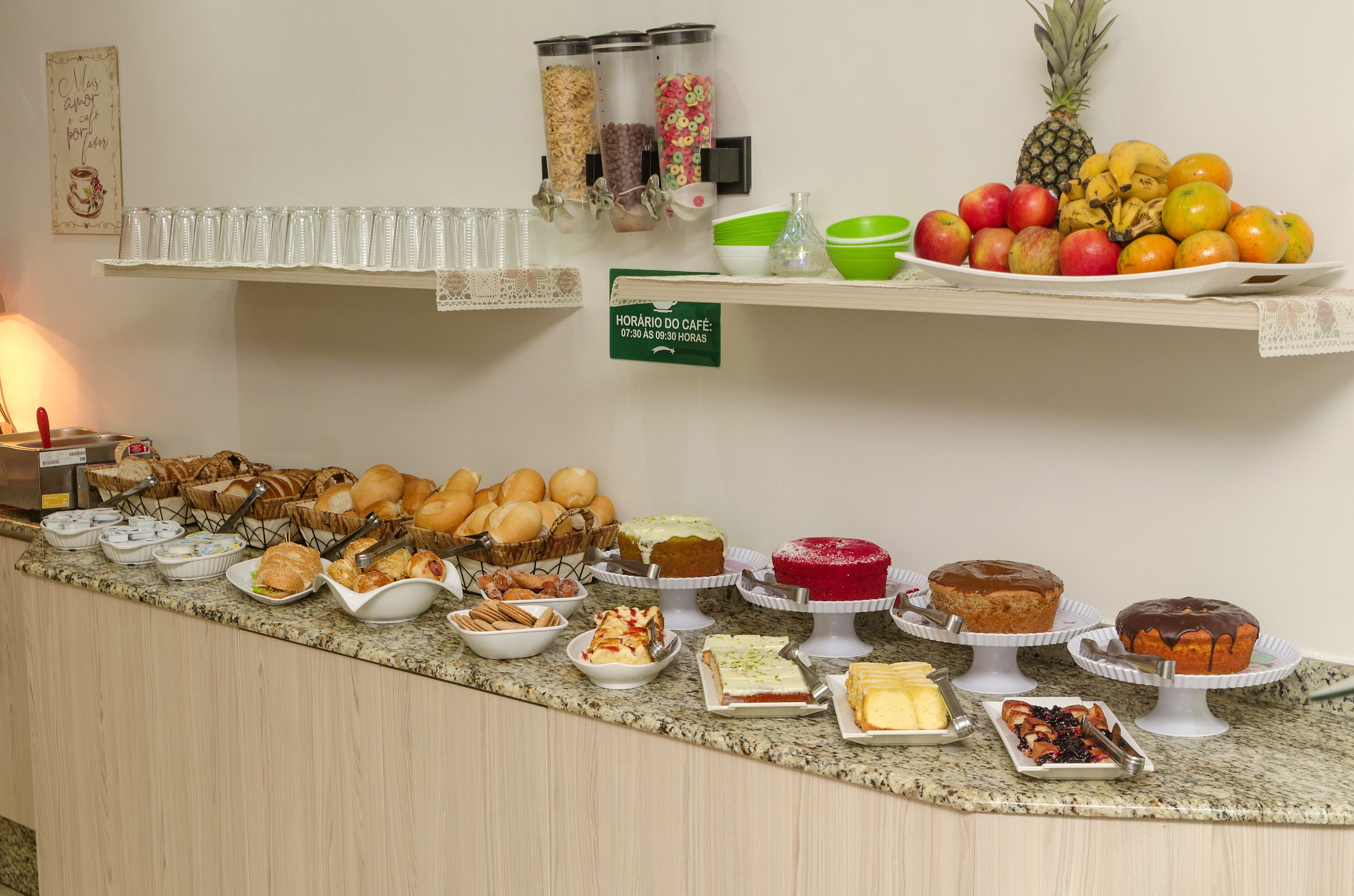 Un bufé con diversas opciones de comida y un cartel que indica el horario del desayuno.