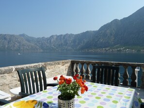 Una mesa con mantel de lunares, un florero con flores y una vista de un lago con montañas al fondo.