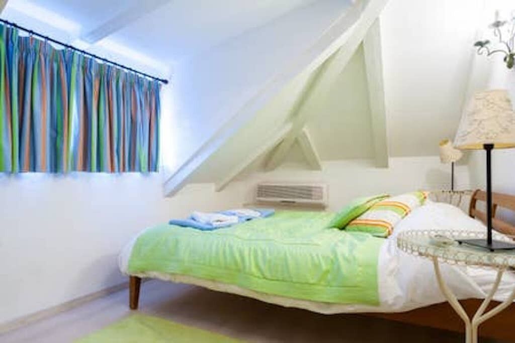A bedroom with a bed, a lamp, and a window with curtains.