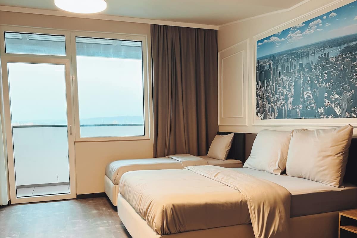 A modern bedroom with a large bed, a cityscape view, and a large window.