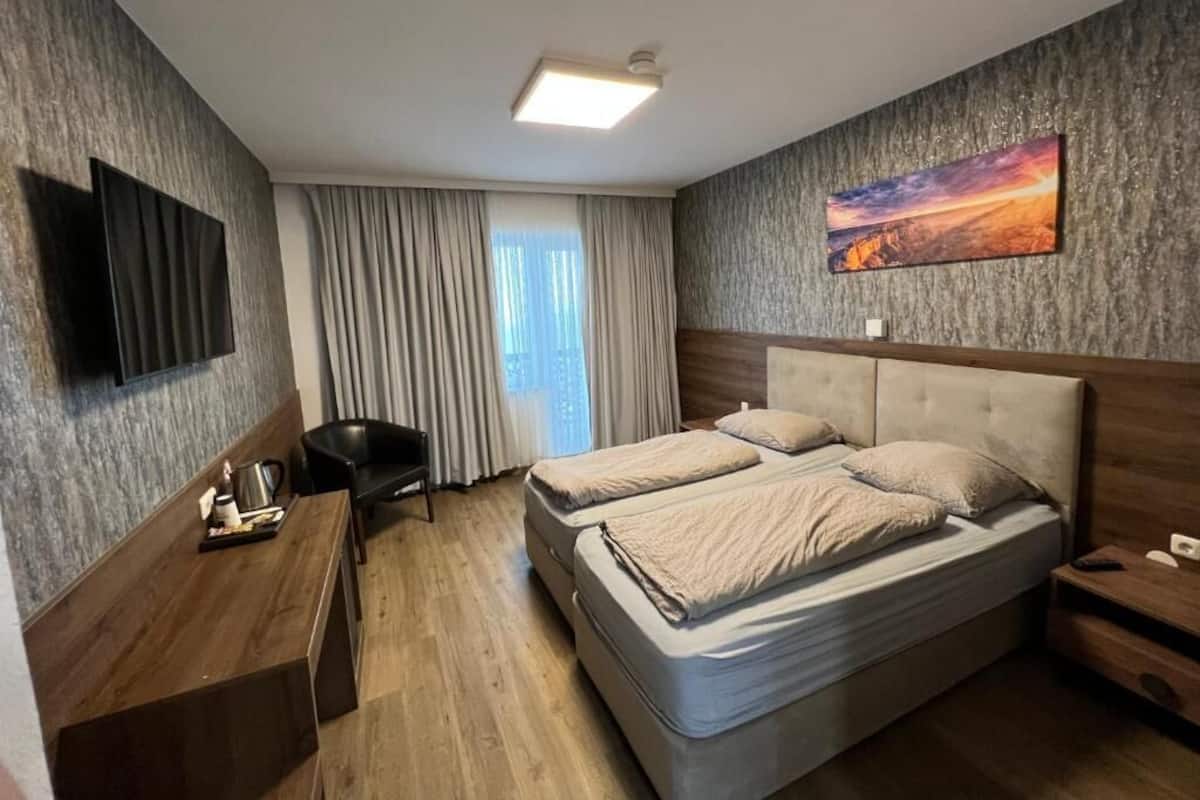 A hotel room with a bed, a desk, a chair, and a TV.