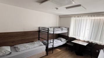 A dormitory room with bunk beds, a desk, and a chair.