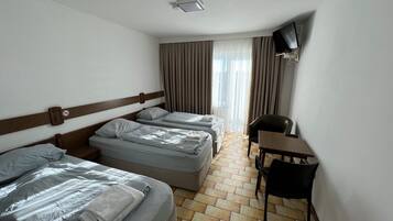 A hotel room with two beds, a desk, and a chair.