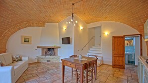 A cozy living room with a fireplace, a dining area, and a staircase leading to an upper level. - Mulignone 9 - Apartment with pool (Molino D'elsa)