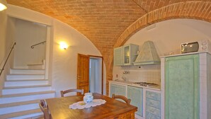 A kitchen with a brick ceiling, a dining table with chairs, and a stove. - Mulignone 9 - Apartment with pool (Molino D'elsa)