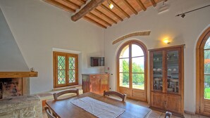 Un comedor con una mesa de madera, sillas, una chimenea y un televisor montado en la pared.