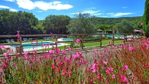 Zona de piscina con valla de madera, césped y vista a un paisaje montañoso.