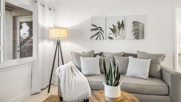 A living room with a grey sofa, a floor lamp, and wall art.
