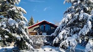 Eine schneebedeckte Lodge mit rotem Dach, umgeben von mit Schnee beladenen Bäumen.