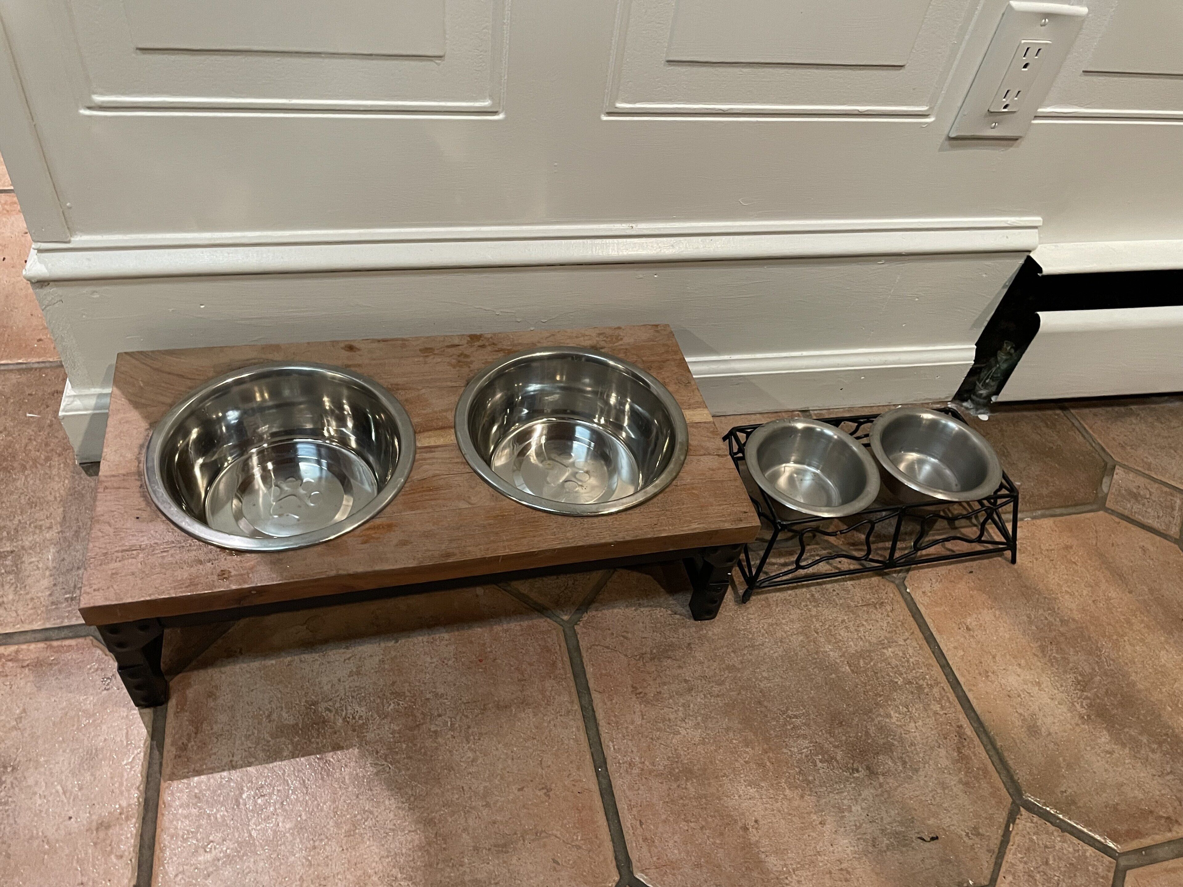 A wooden feeding station with two bowls on the left and two bowls on a wire rack on the right.