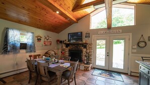 Ein Essbereich mit Kamin aus Stein, Holzboden und einem Fernseher auf einem Regal.