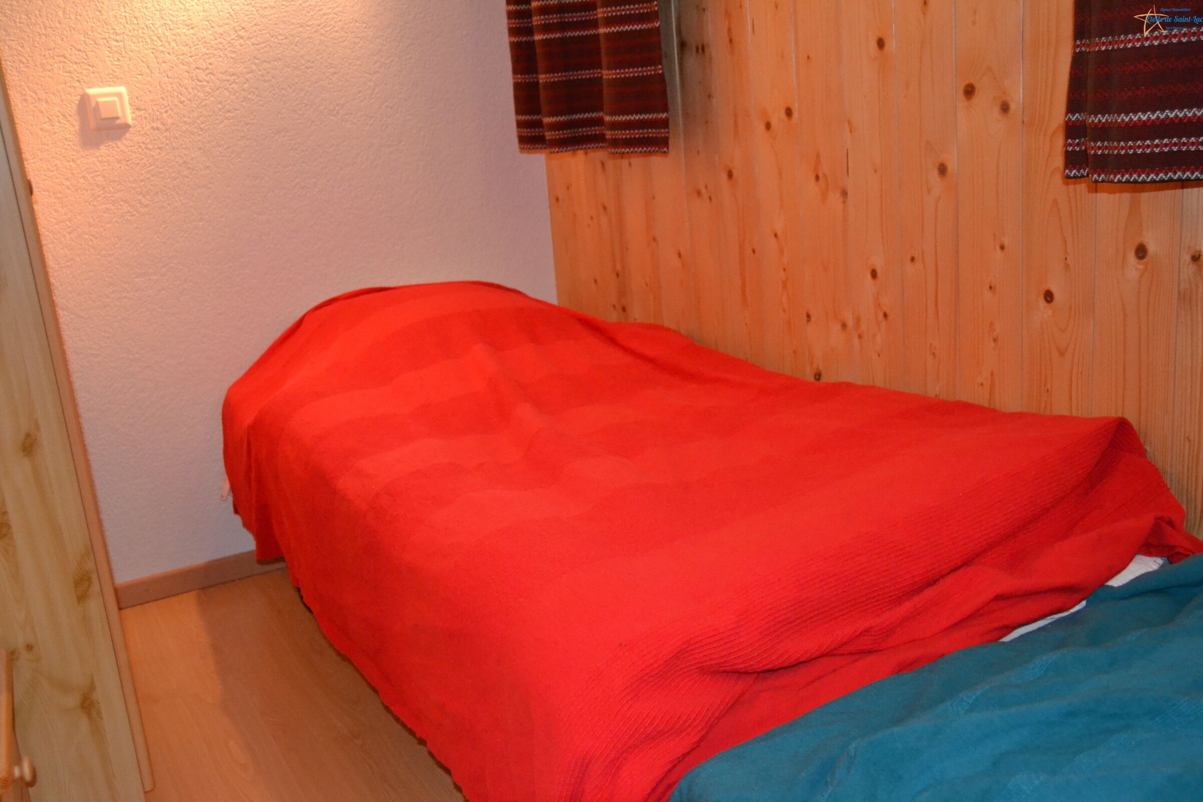 Une petite chambre avec un lit simple, un mur en bois et un plafond blanc.