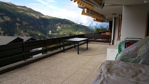 A balcony with a table and chairs, overlooking a mountainous landscape. - Outside : flat for 6 persons ground floor, 40sqm south-facing balcony -Inside : about 77 sqm, open k (St-Luc)