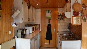 A compact kitchen with wooden cabinets, a microwave, a sink, and a hanging apron. - Outside : Apartment for 4-6 people, balcony with beautiful view -Inside : 65 sqm, living with , dine (St-Luc)