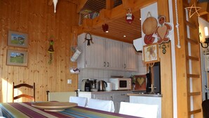 A cozy room with a bed, a small kitchenette, and wooden walls. - Outside : Apartment for 4-6 people, balcony with beautiful view -Inside : 65 sqm, living with , dine (St-Luc)