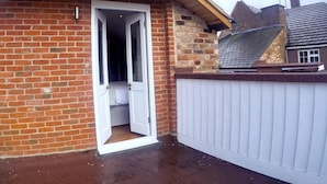 A small, single-story brick building with a white door leading to a narrow hallway. - The Courtyard (Bewdley)
