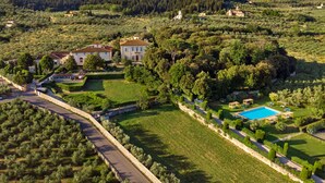 Un vaste domaine comprenant plusieurs bâtiments, une piscine et un jardin bien entretenu.