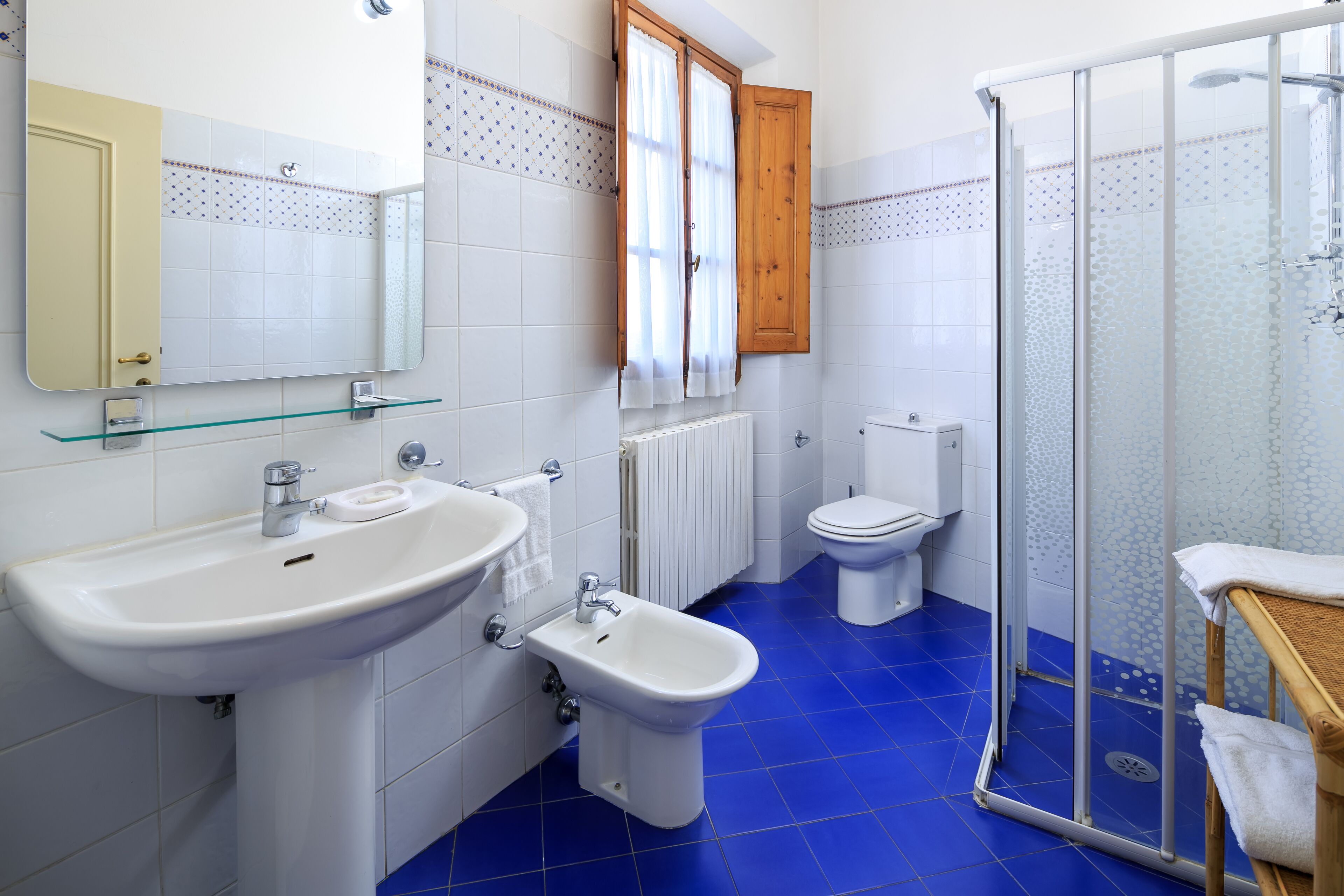 Une salle de bain avec un lavabo blanc, un bidet, des toilettes et une douche à parois de verre.
